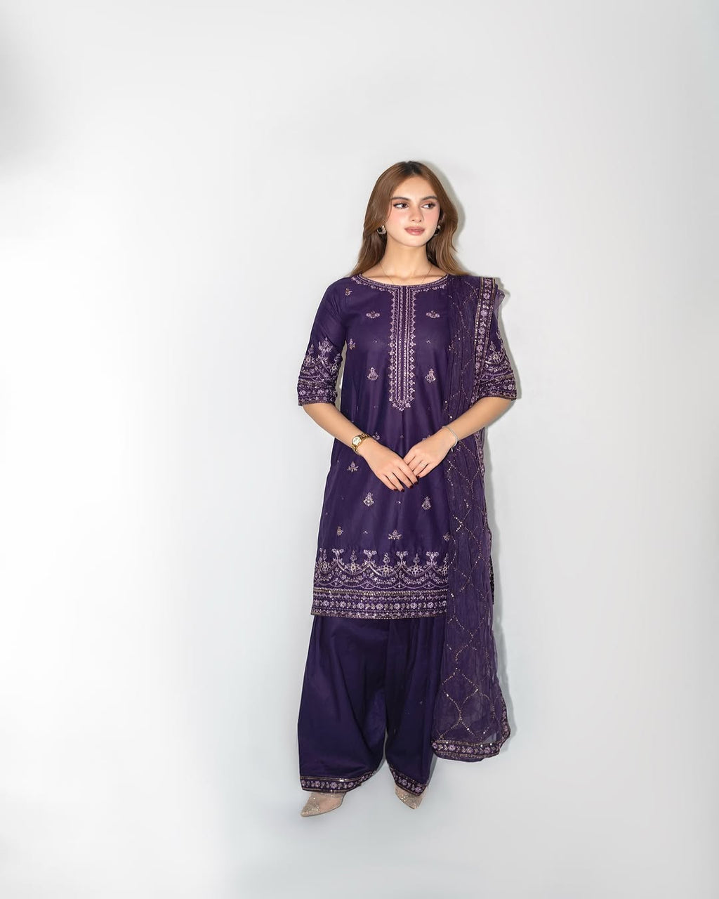 Woman wearing a purple embroidered outfit on a white background